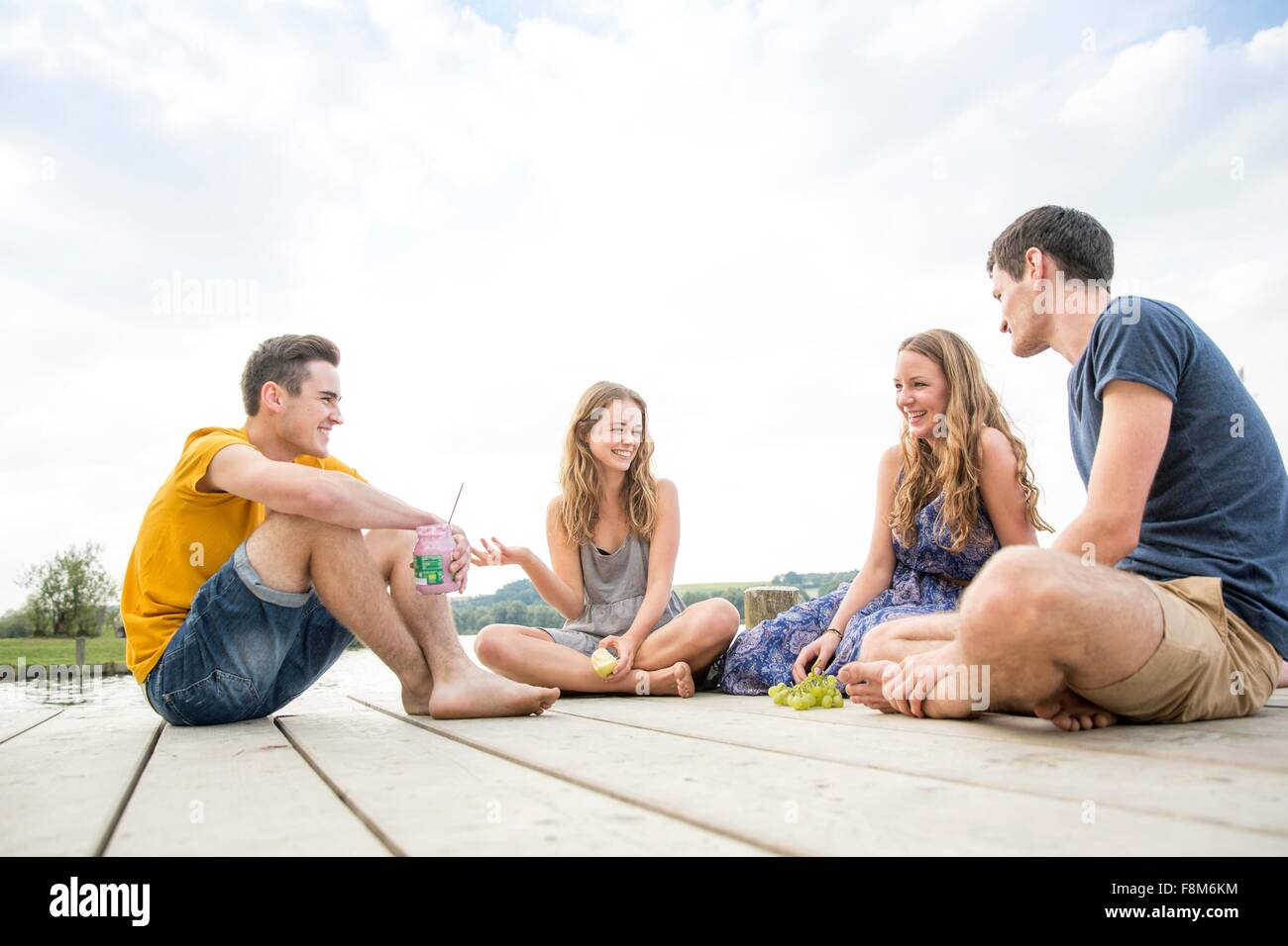 Groupe de jeunes adultes sitting on Jetty, relaxant Banque D'Images
