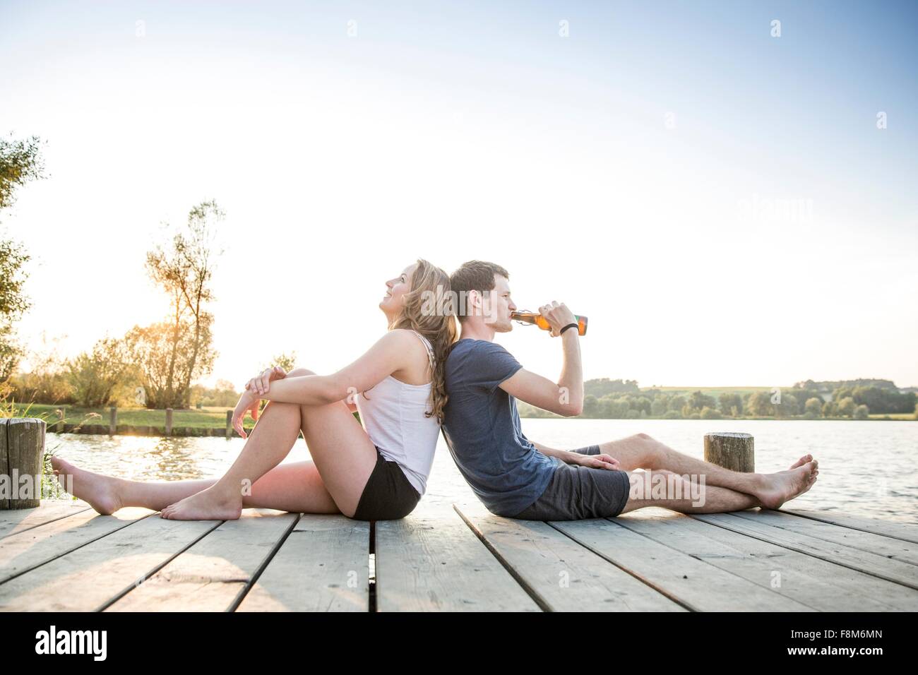 Young couple relaxing on Jetty, assis dos à dos Banque D'Images