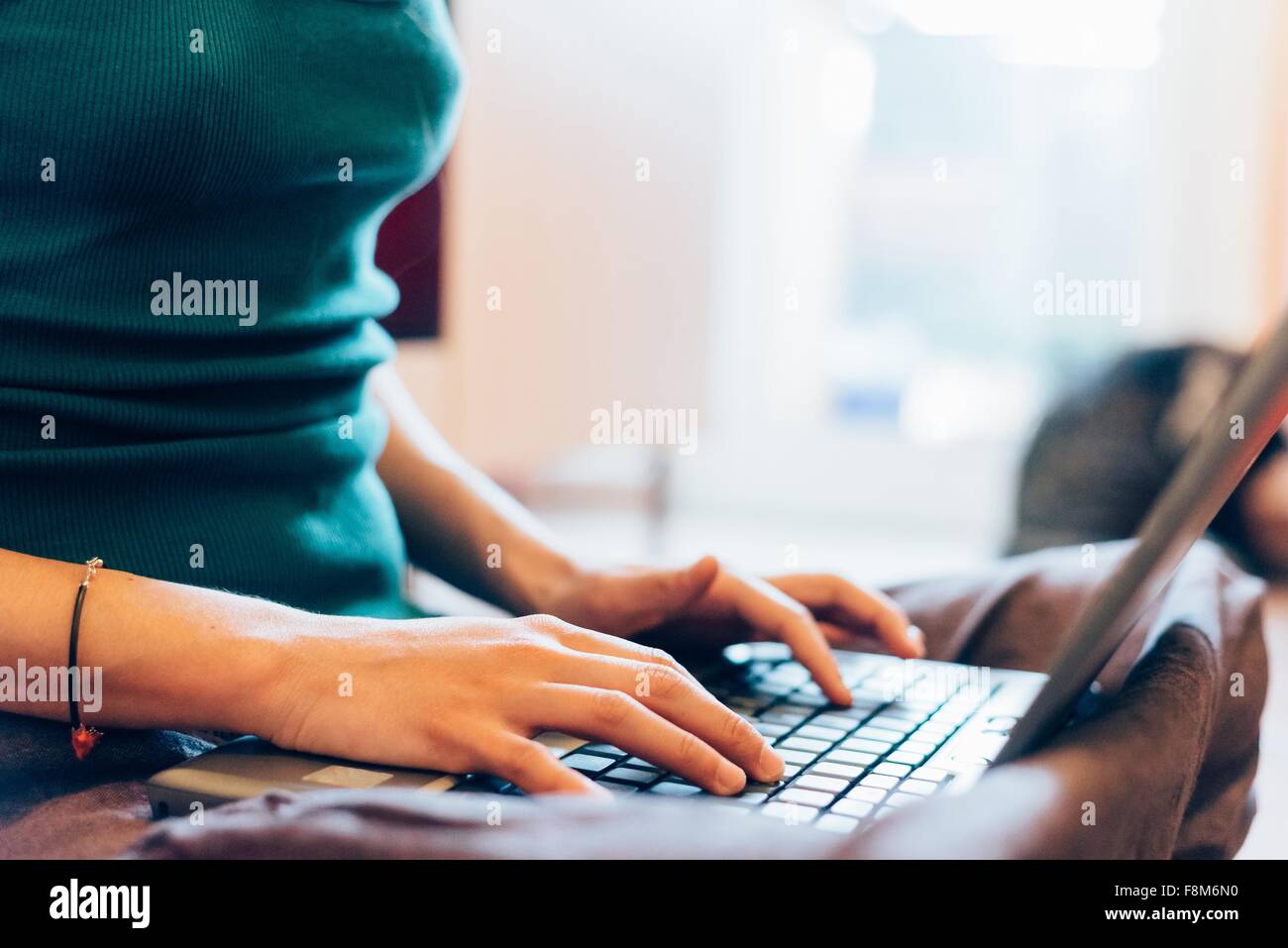 Cropped mid section of mid adult woman typing on laptop computer Banque D'Images