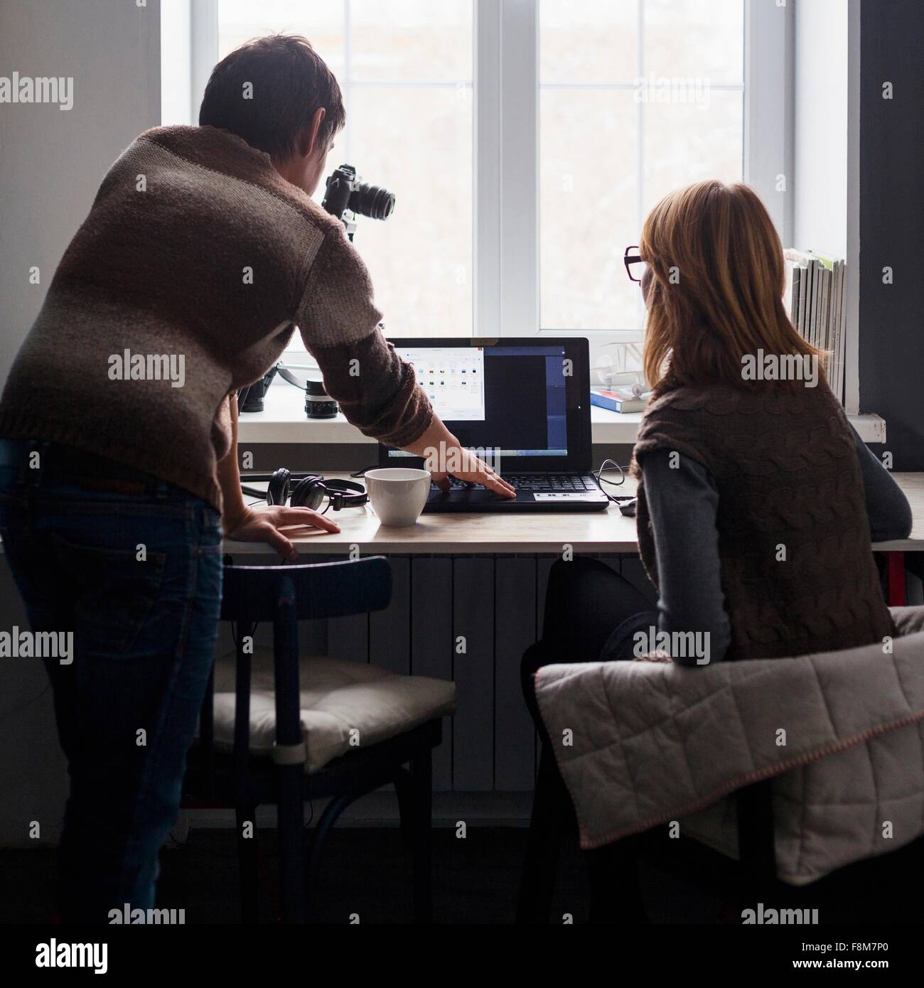Mid adult man and woman using laptop at 24, vue arrière Banque D'Images