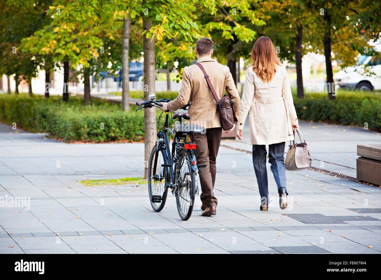 Businessman et woman pushing bike Banque D'Images
