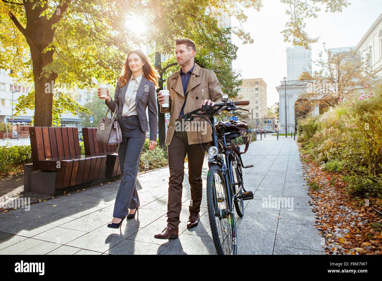 Businessman et woman pushing bike through park Banque D'Images