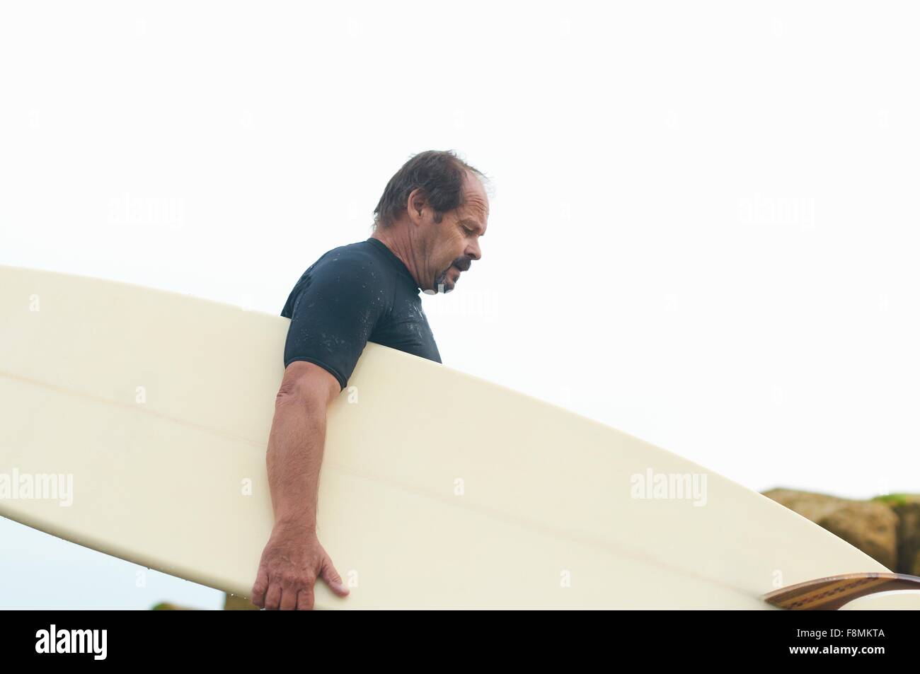 Surfer carrying surfboard Banque D'Images