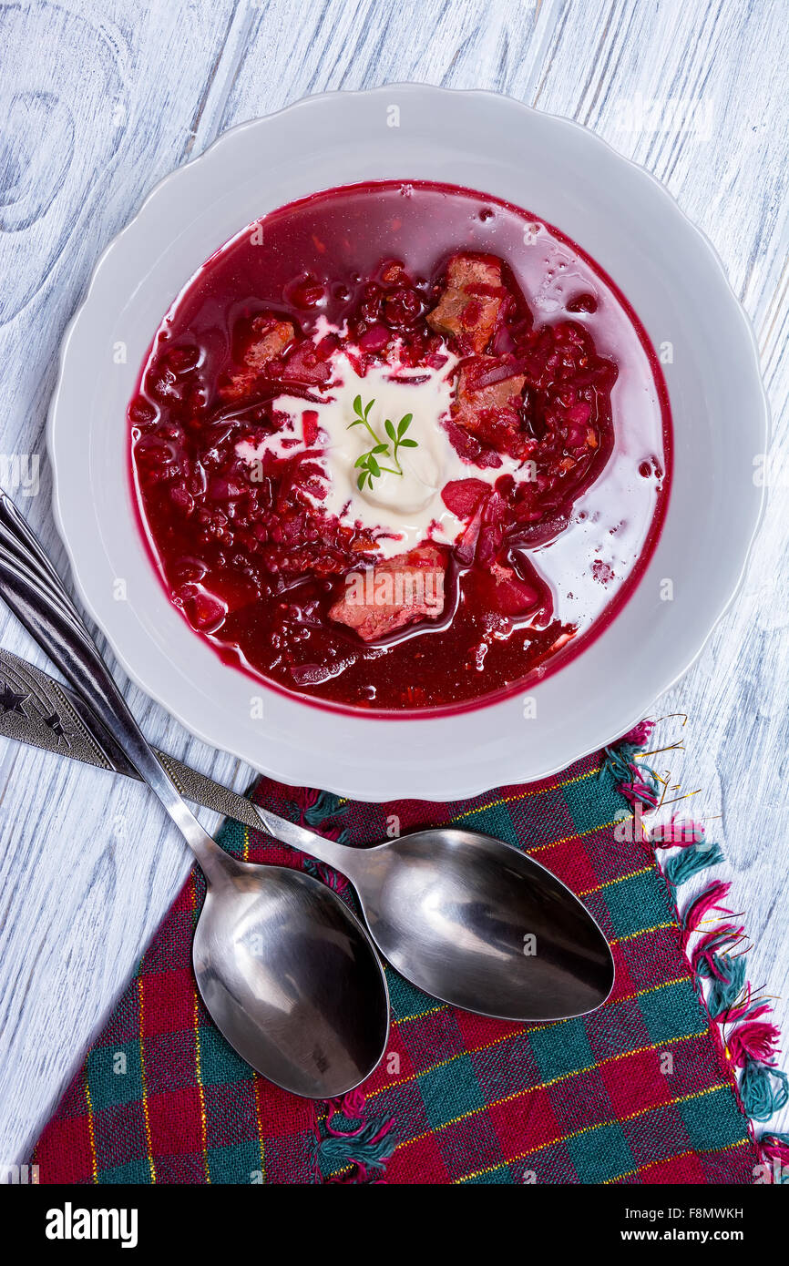 Soupe de betteraves, cuillère, serviette sur fond de bois. Une cuisine traditionnelle ukrainienne Banque D'Images