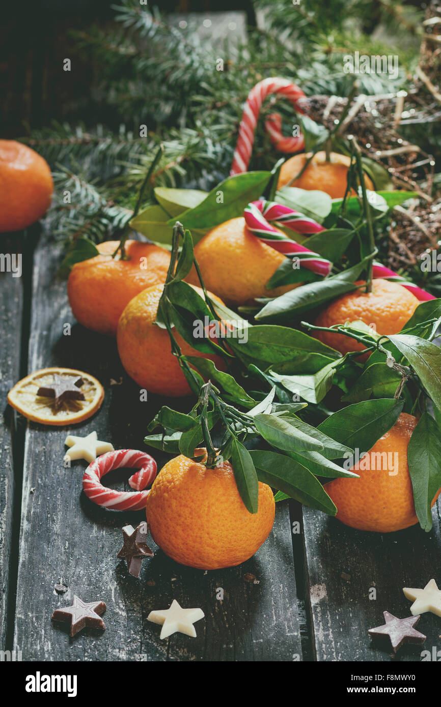 Mandarine avec des feuilles dans un décor de Noël avec l'arbre de Noël, l'orange et les bonbons à sec plus vieille table en bois. Banque D'Images