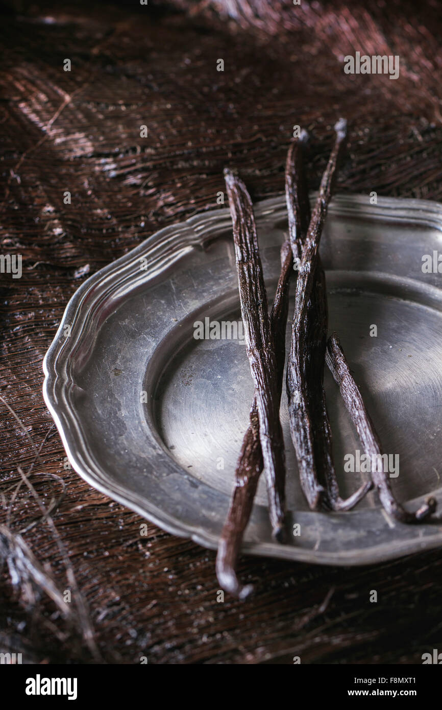 Tas de bâtons de vanille en vintage metal plaque sur palm sombre croûte. Banque D'Images