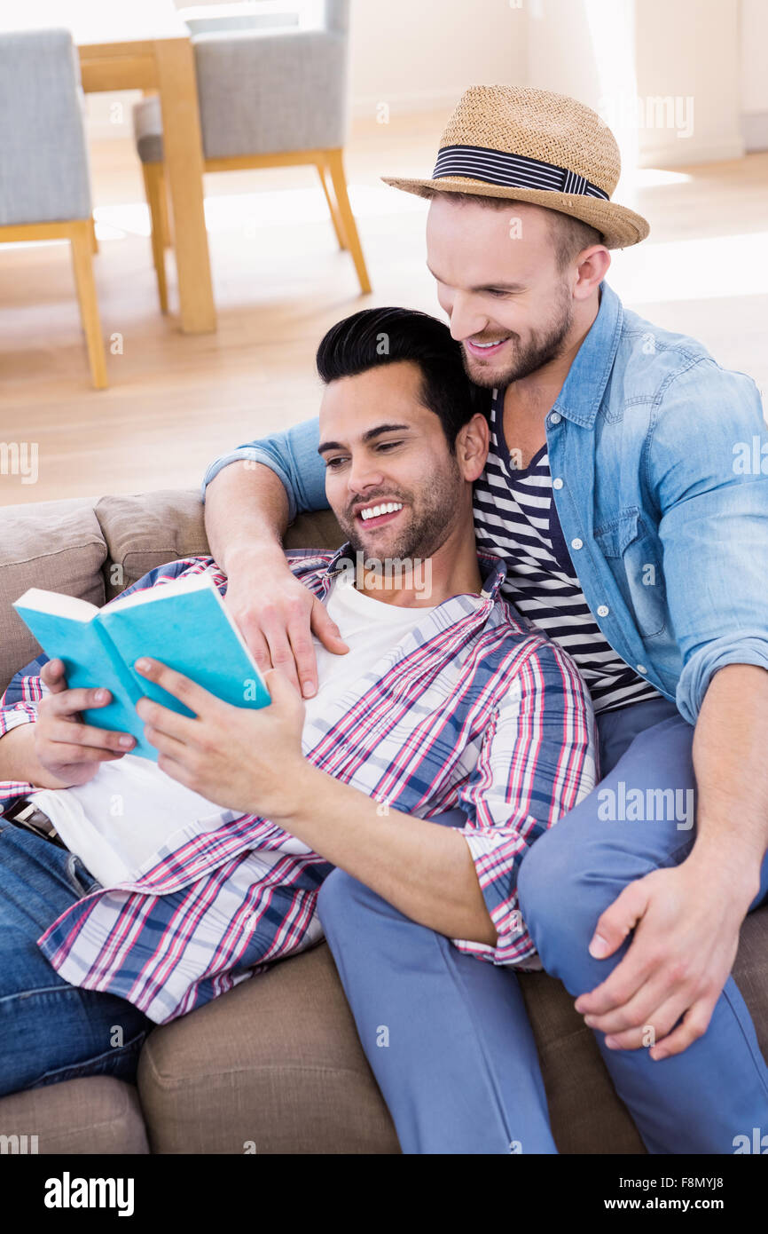 Gay couple relaxing on the couch reading book Banque D'Images