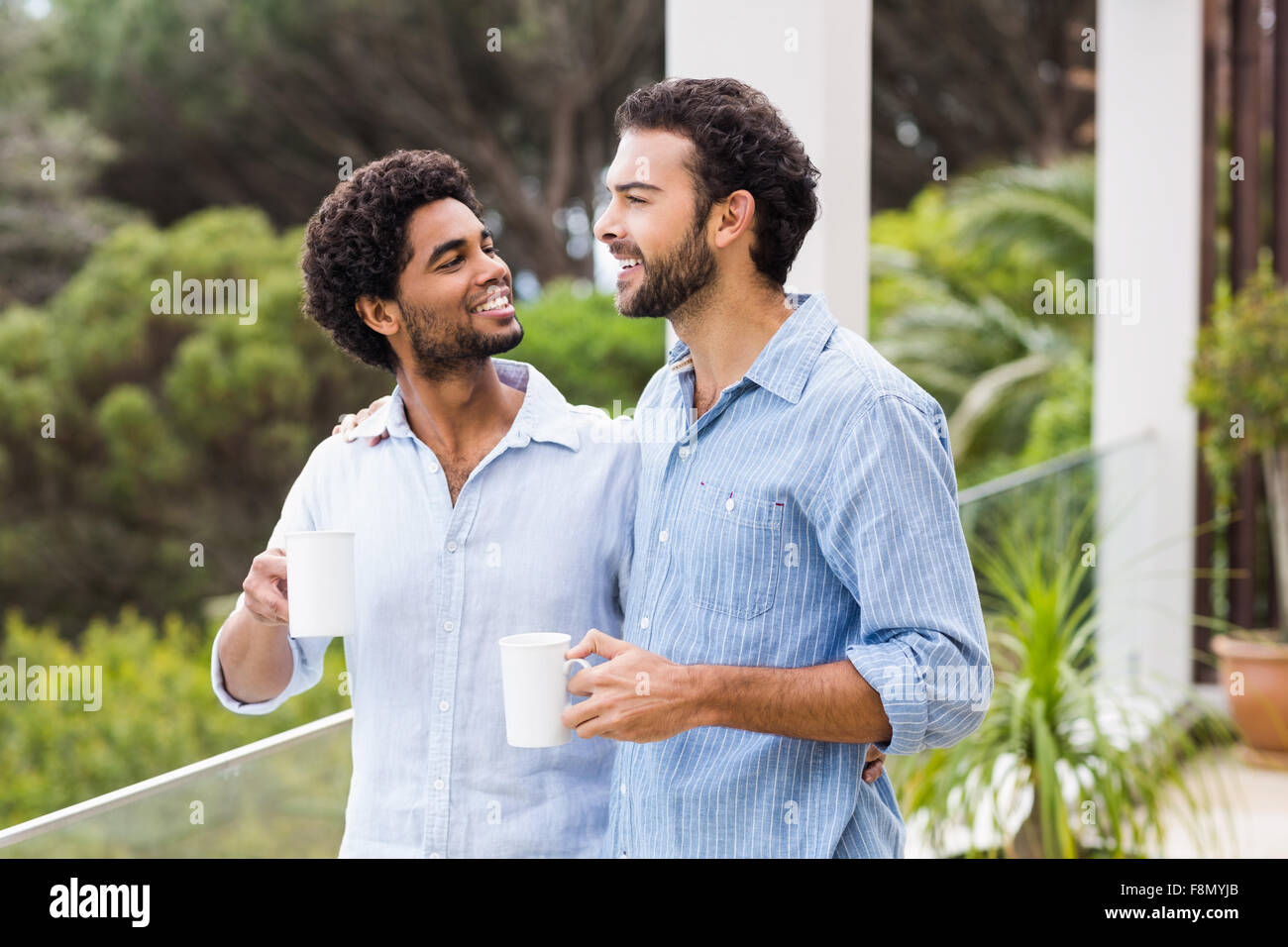 Smiling gay couple holding tasses et parler Banque D'Images