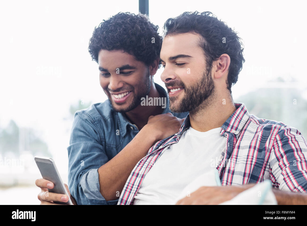 Happy gay couple using smartphone Banque D'Images