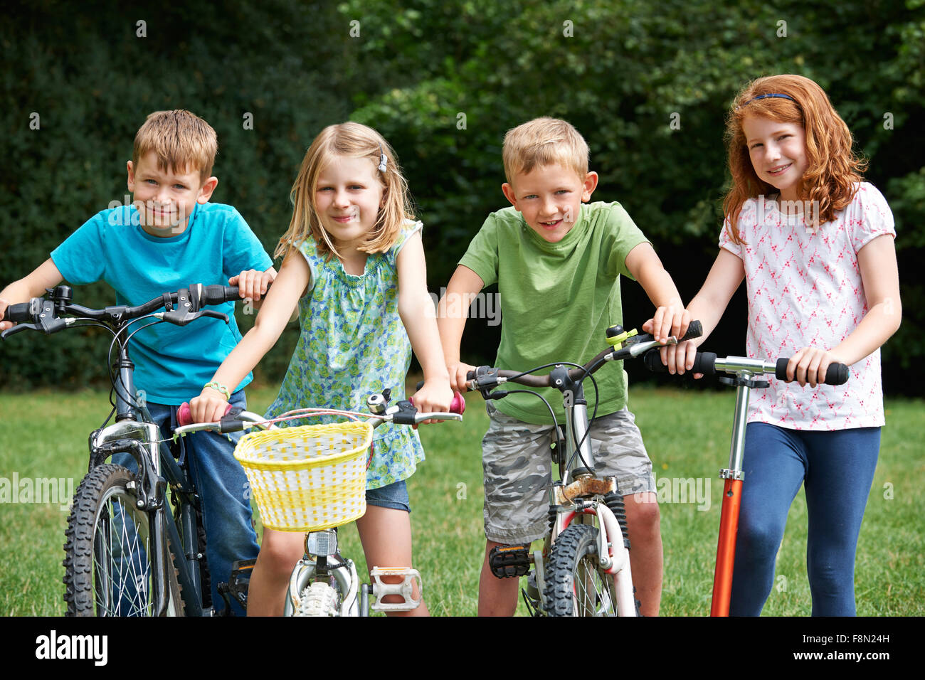 Groupe d'enfants jouant sur des vélos et scooters Banque D'Images