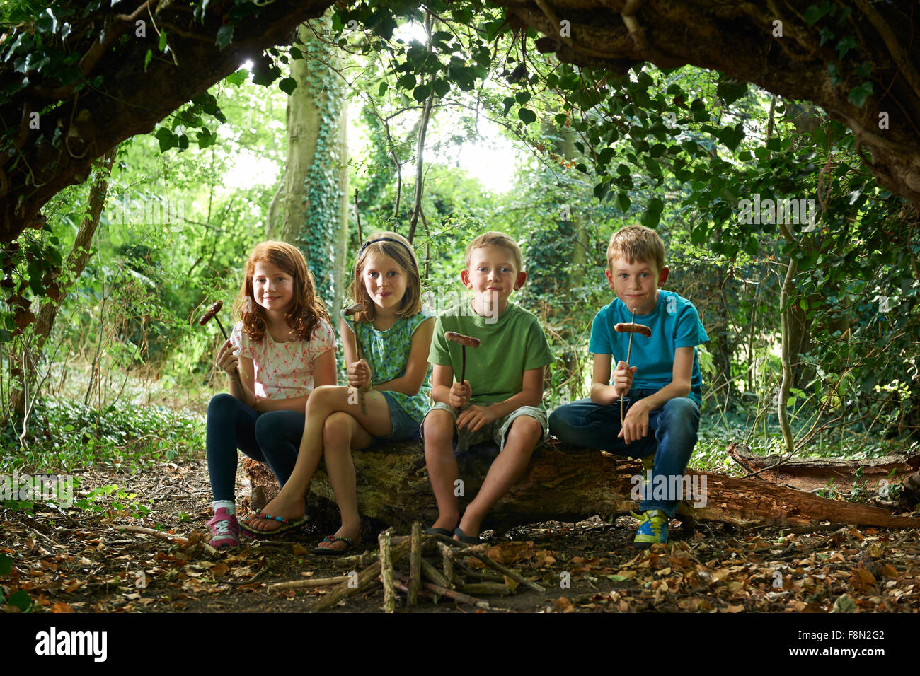 Groupe d'enfants de manger les saucisses dans le camp des bois Banque D'Images