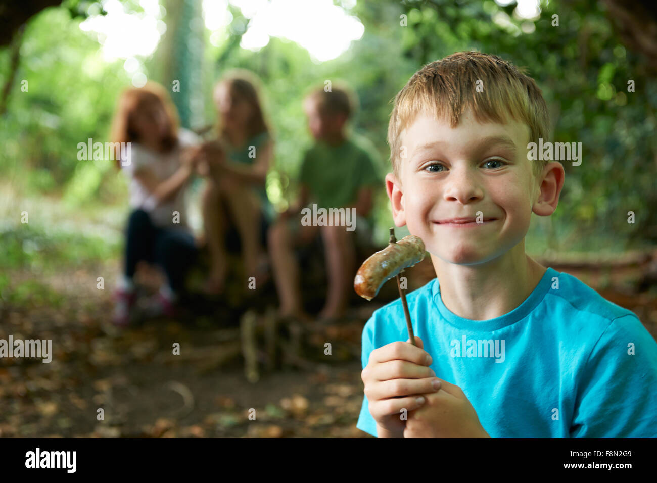 Groupe d'enfants de manger les saucisses dans le camp des bois Banque D'Images