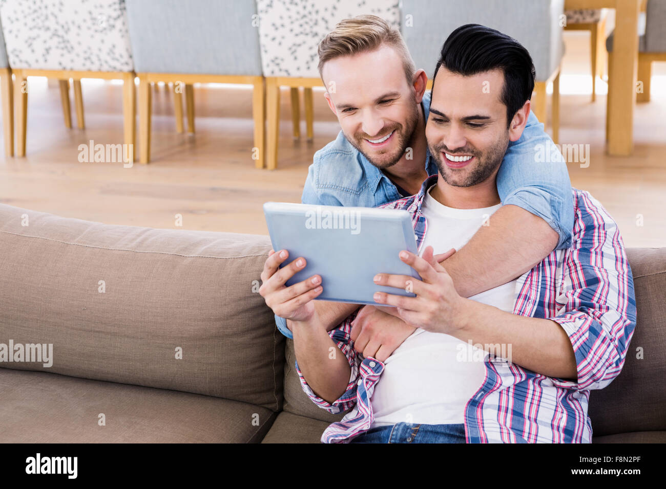 Couple Gay, se détendre sur la table à l'aide de tablet Banque D'Images