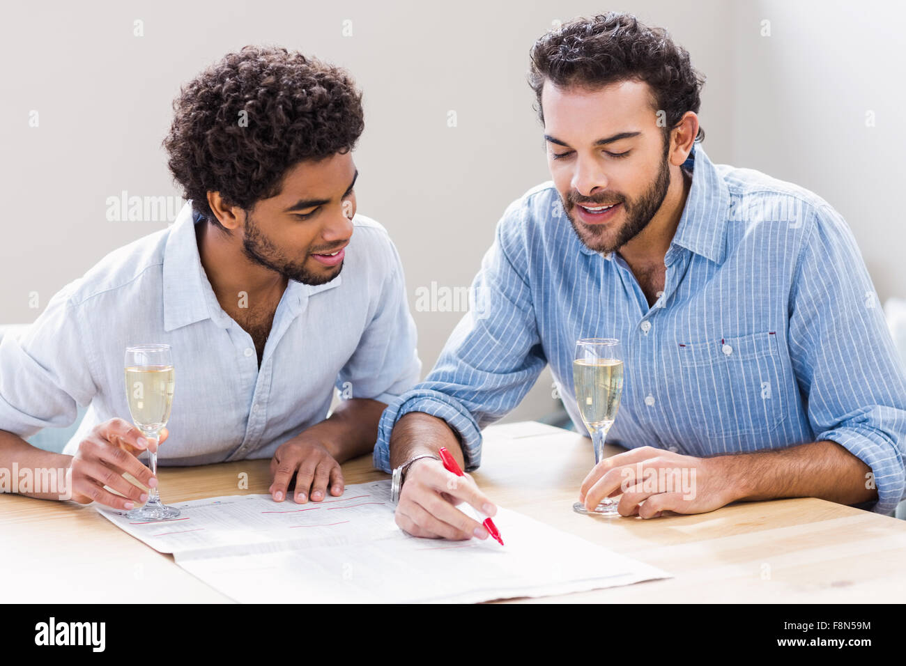 Happy gay couple drinking champagne et écrit le journal Banque D'Images