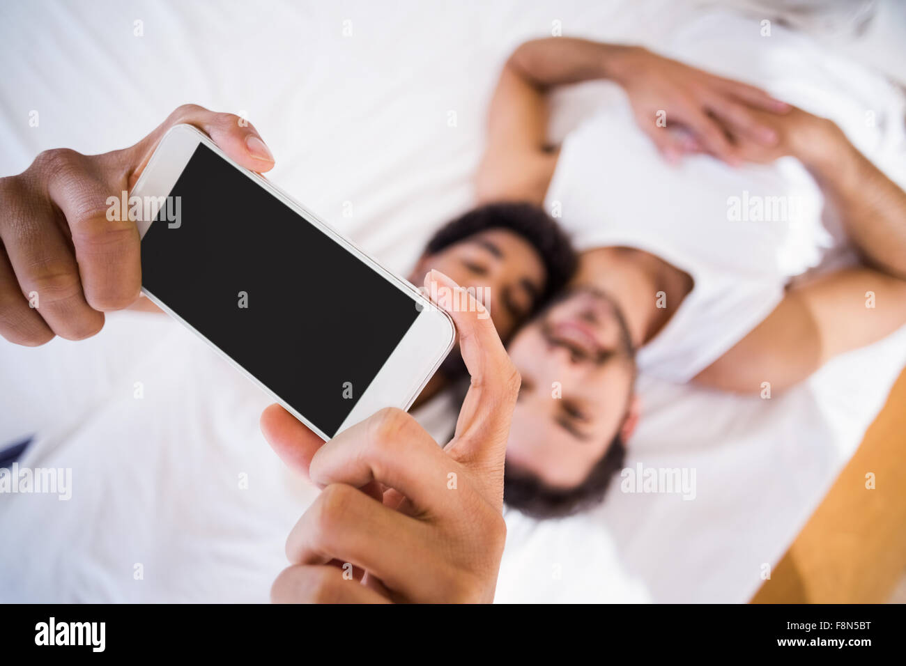 Heureux couple gay en tenant sur selfies bed Banque D'Images