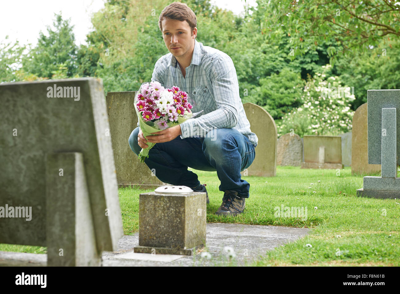 Placer l'homme par Pierre tombale cimetière de fleurs Banque D'Images