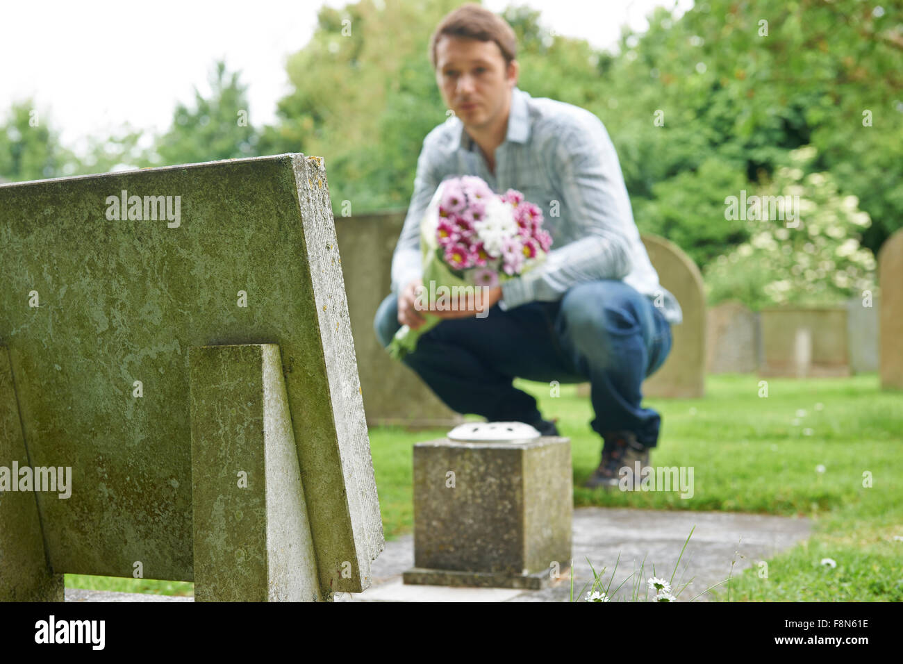 Placer l'homme par Pierre tombale cimetière de fleurs Banque D'Images