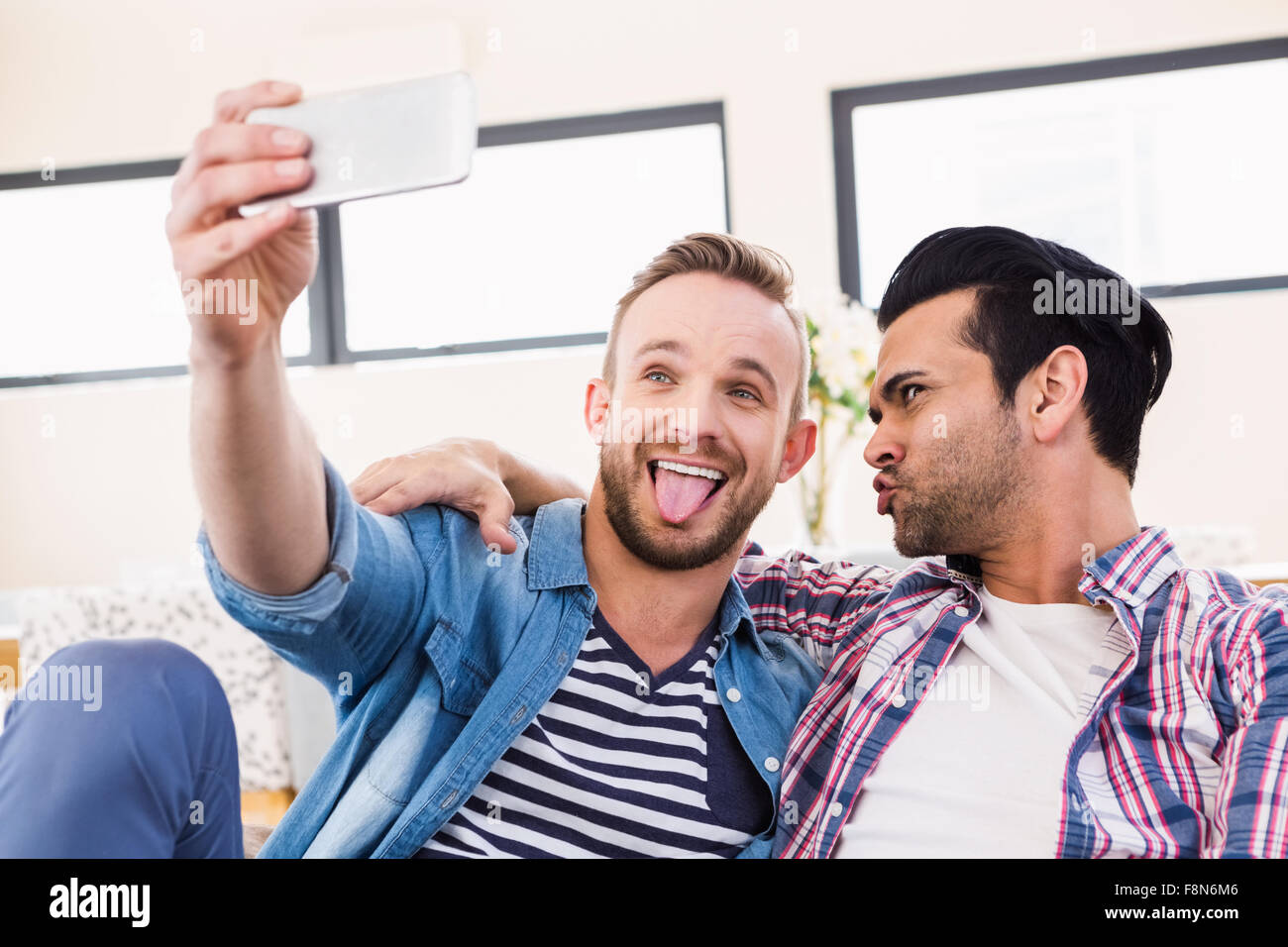 Couple Gay de détente sur le canapé en prenant selfies Banque D'Images
