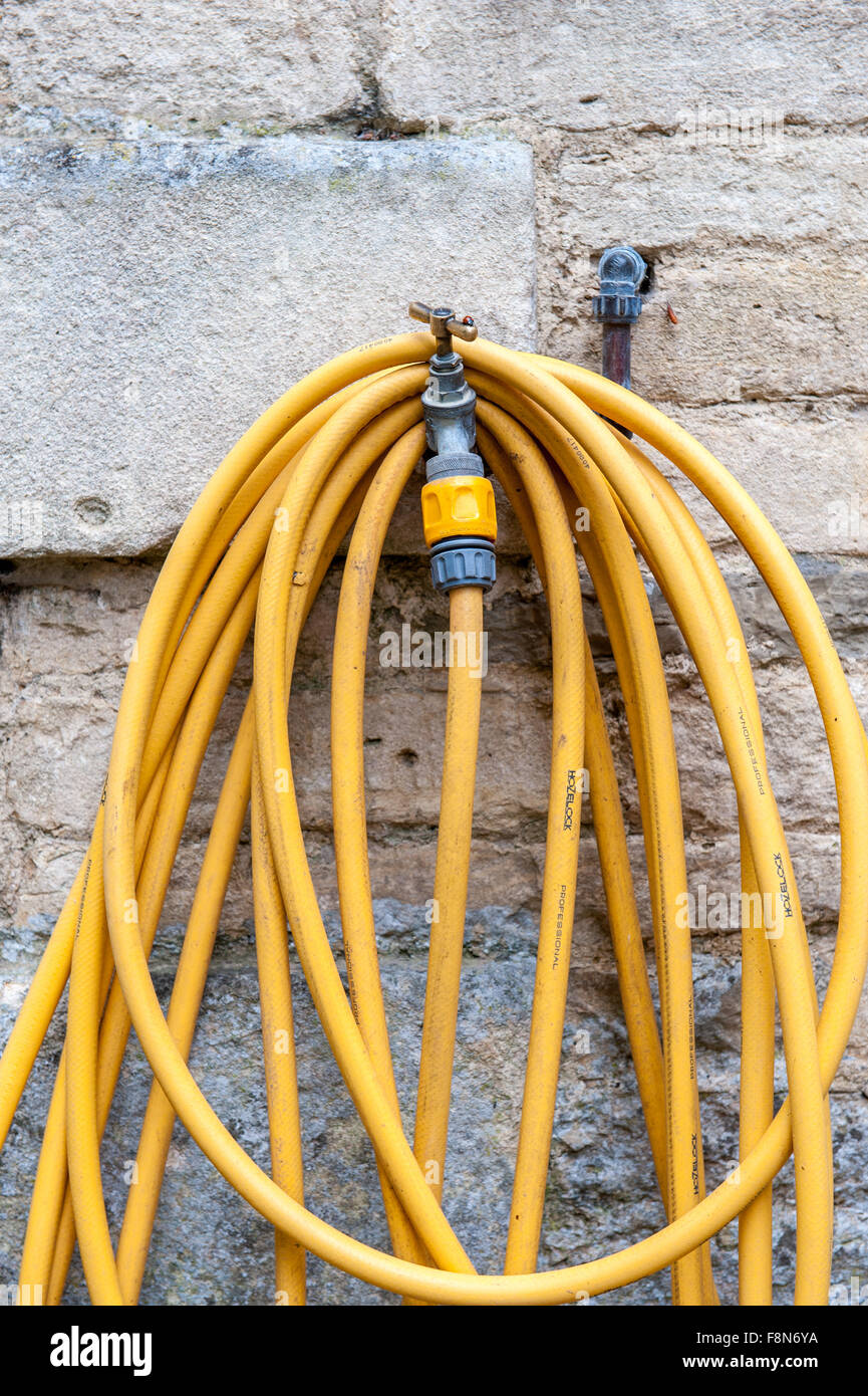 Jardin jaune flexible et un robinet extérieur Banque D'Images