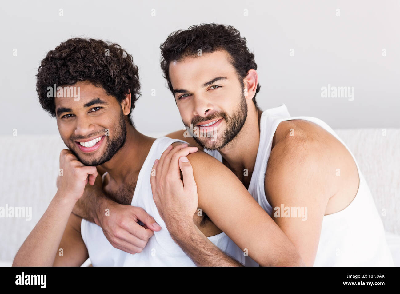 Smiling gay couple hugging on bed Banque D'Images
