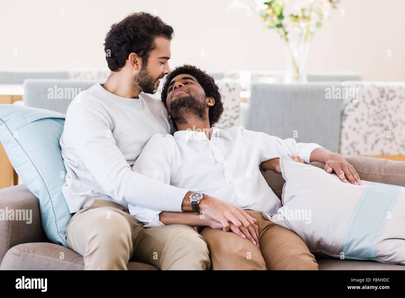 Happy gay couple relaxing on sofa Banque D'Images