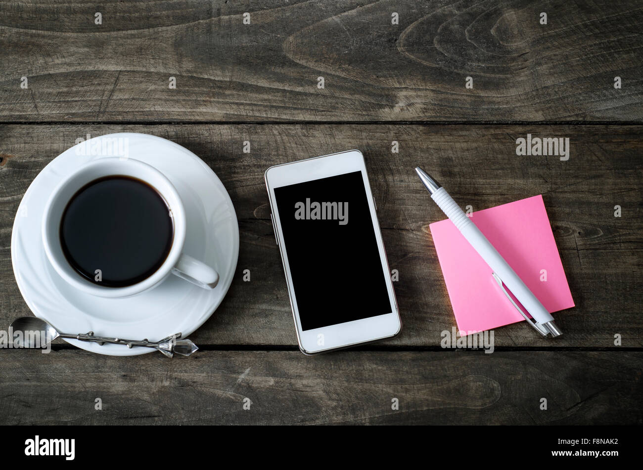 Téléphone avec sticky note papier et tasse de café sur le vieux bureau en bois. Banque D'Images
