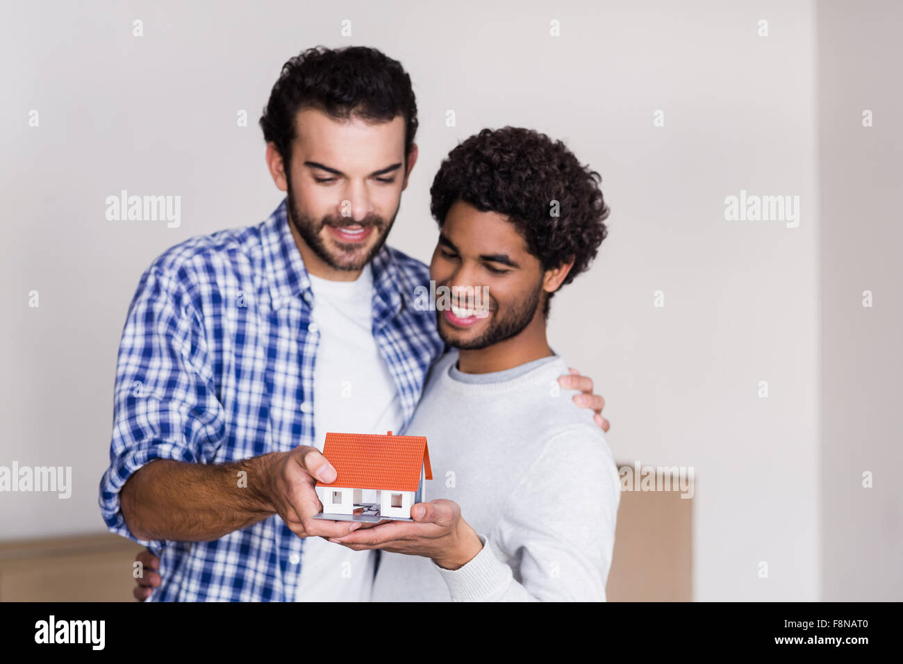 Happy gay couple holding miniature house model Banque D'Images