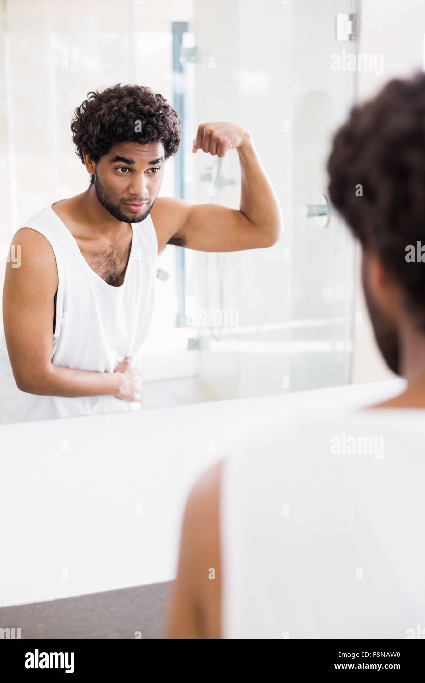 Smiling man looking at ses biceps dans mirror Banque D'Images