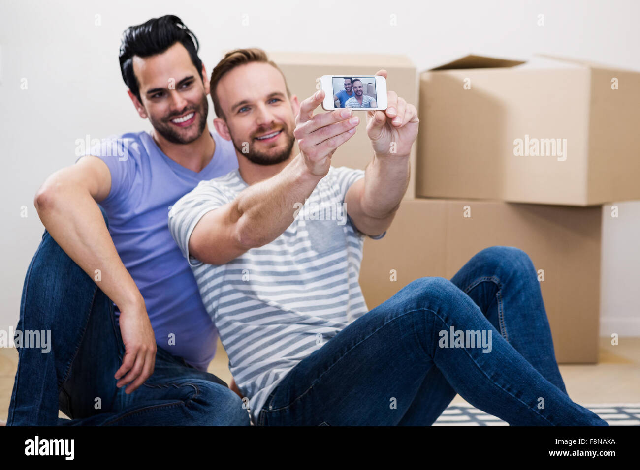 Couple Gay en tenant dans leur nouvelle maison selfies Banque D'Images