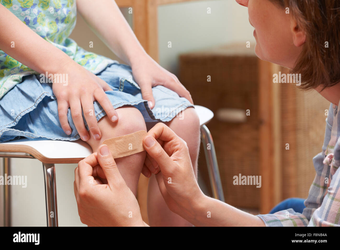Mère d'appliquer l'adhésif à bandage du genou de fille Banque D'Images