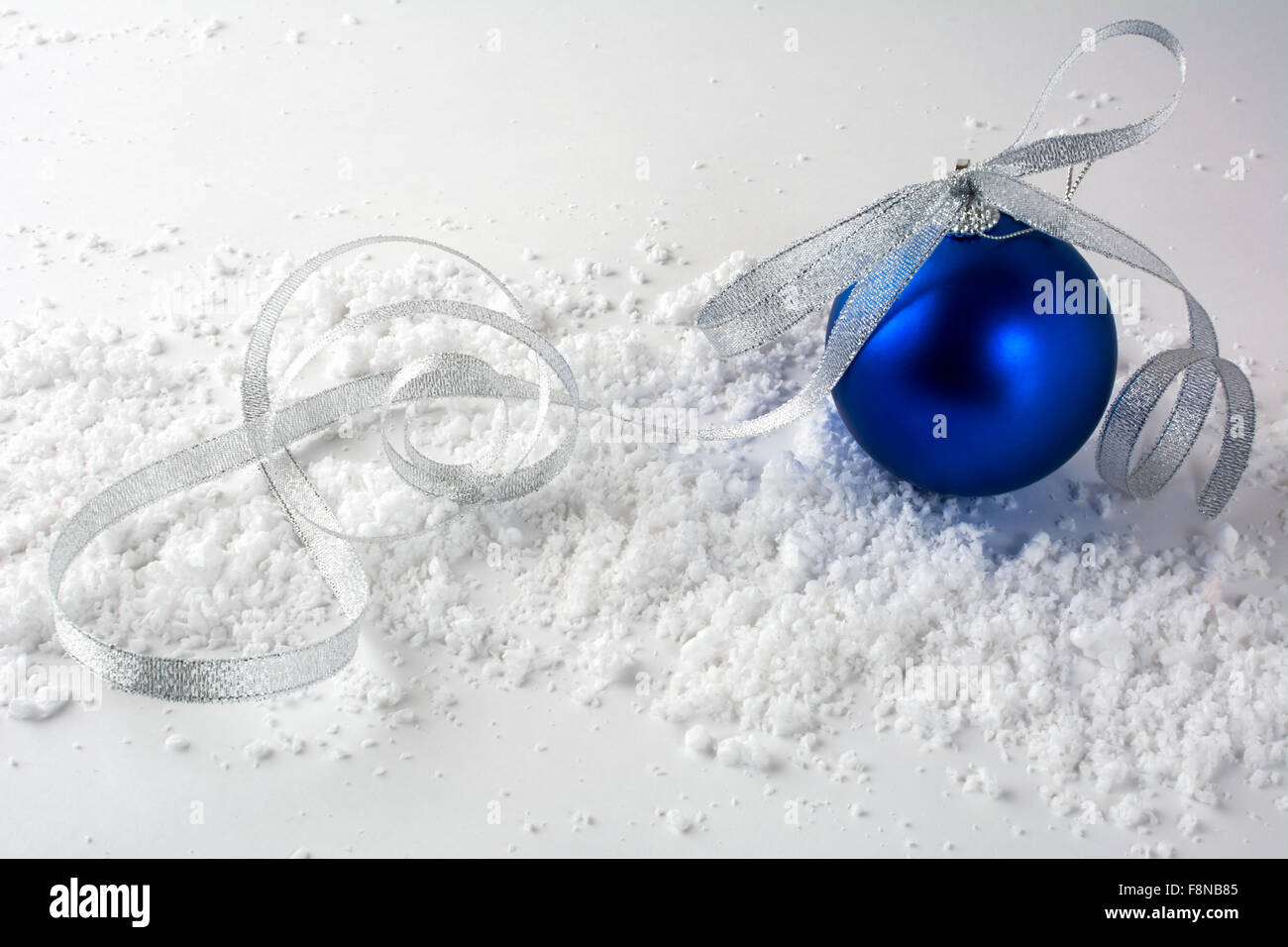 Ornement de Noël Boule Bleu profond avec silver bow dans la neige sur un fond blanc Banque D'Images