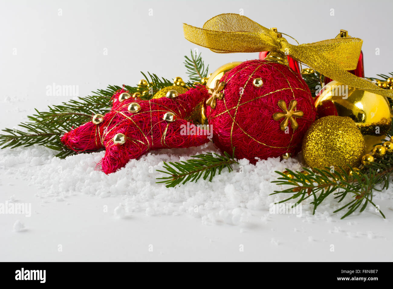 Rouge noël ornement de paille et de boules d'or, dans les branches de sapin de neige sur un fond blanc Banque D'Images