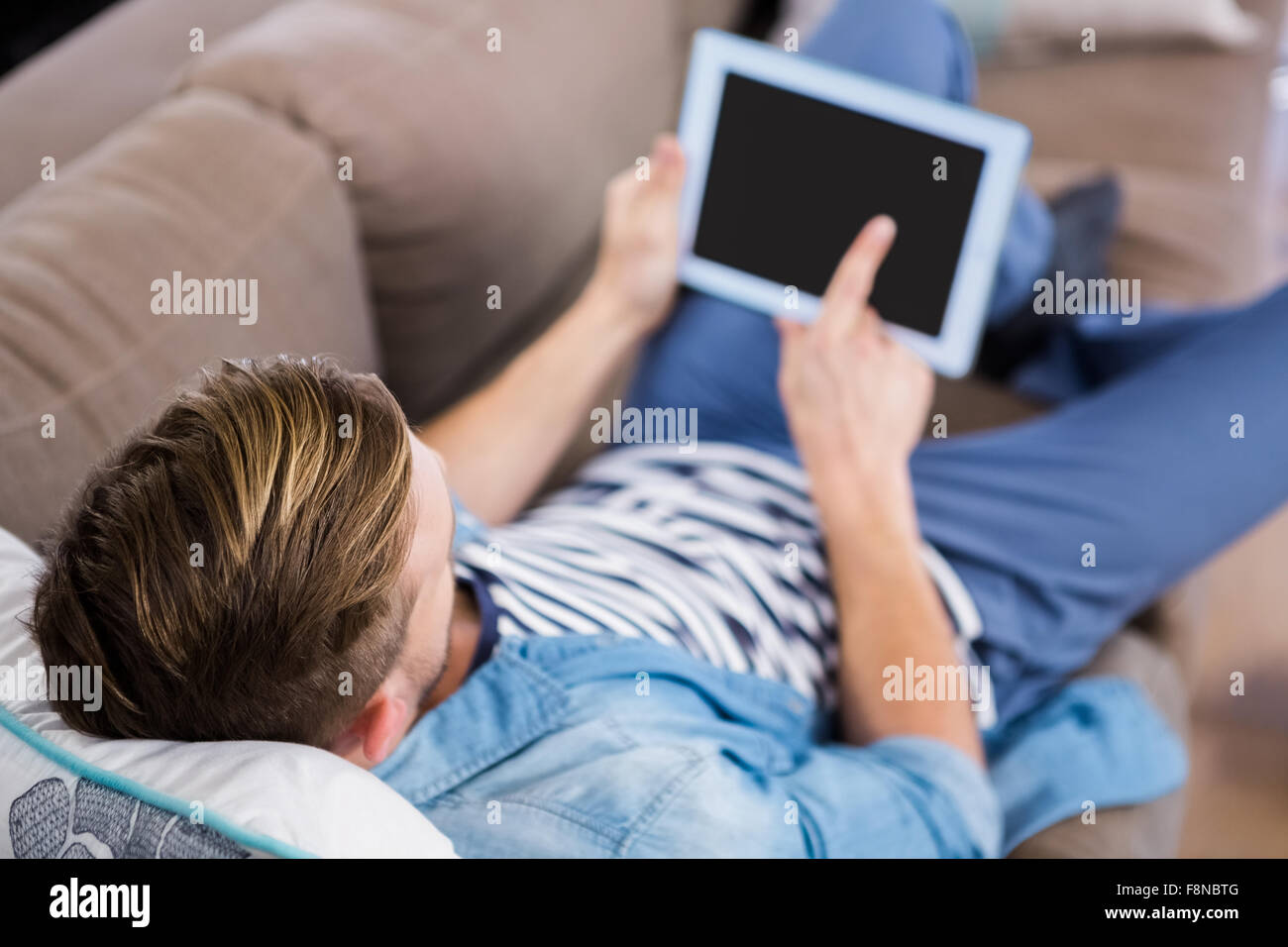 Casual man using tablet on sofa Banque D'Images