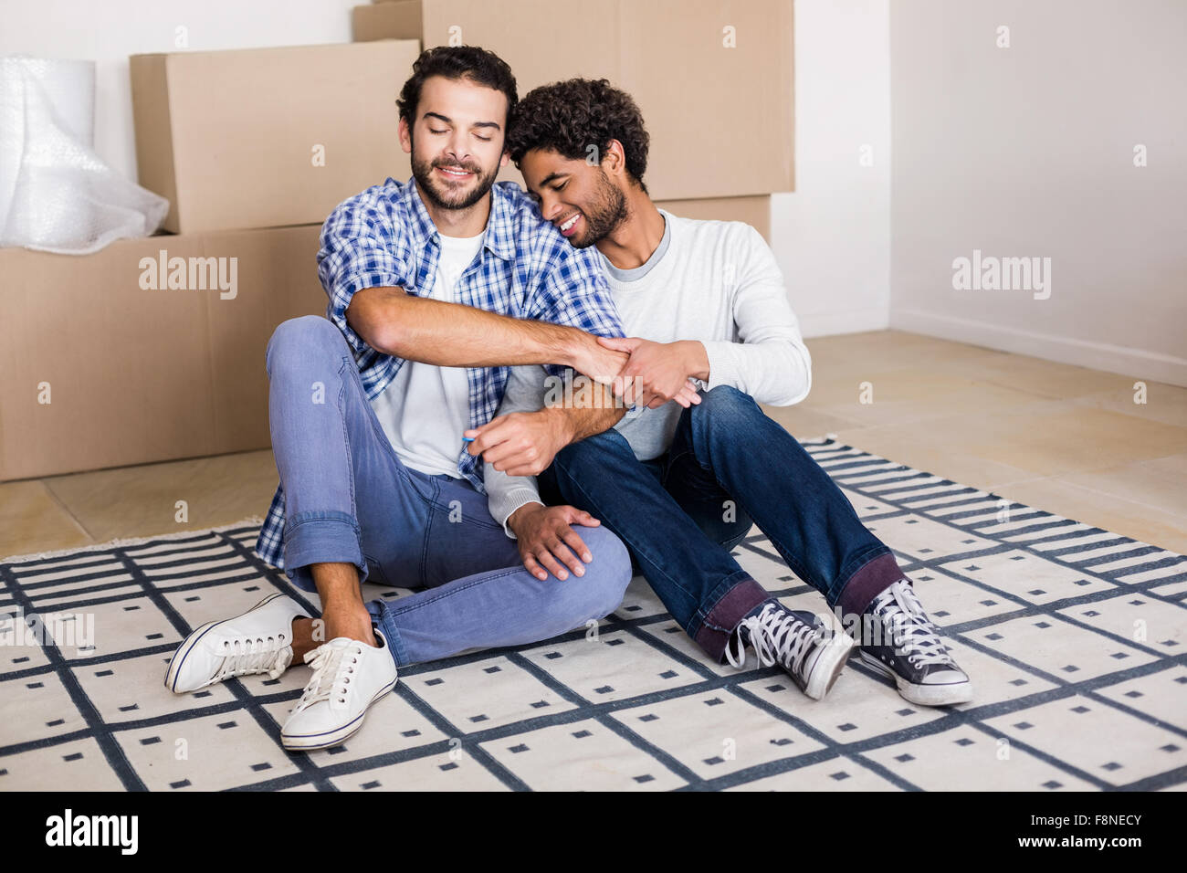 Happy gay couple sitting on floor Banque D'Images