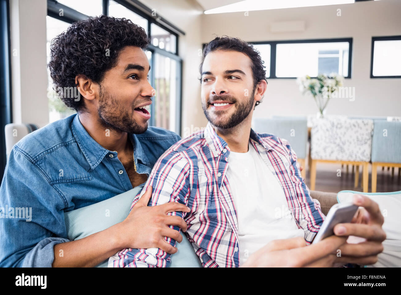Heureux couple gay en conversation sur canapé Banque D'Images