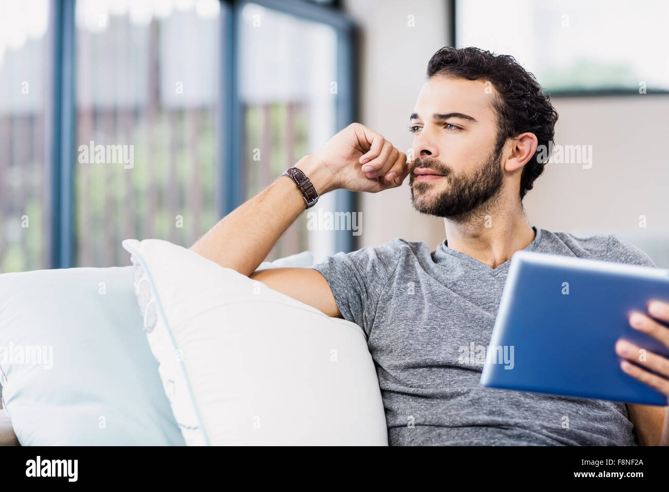 Thoughtful man holding tablet Banque D'Images