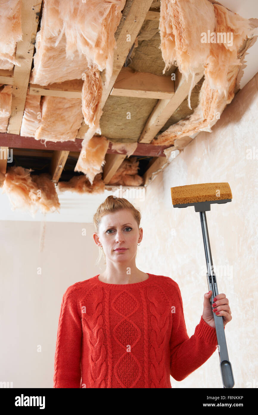 Woman Holding Mop sous plafond endommagé Banque D'Images