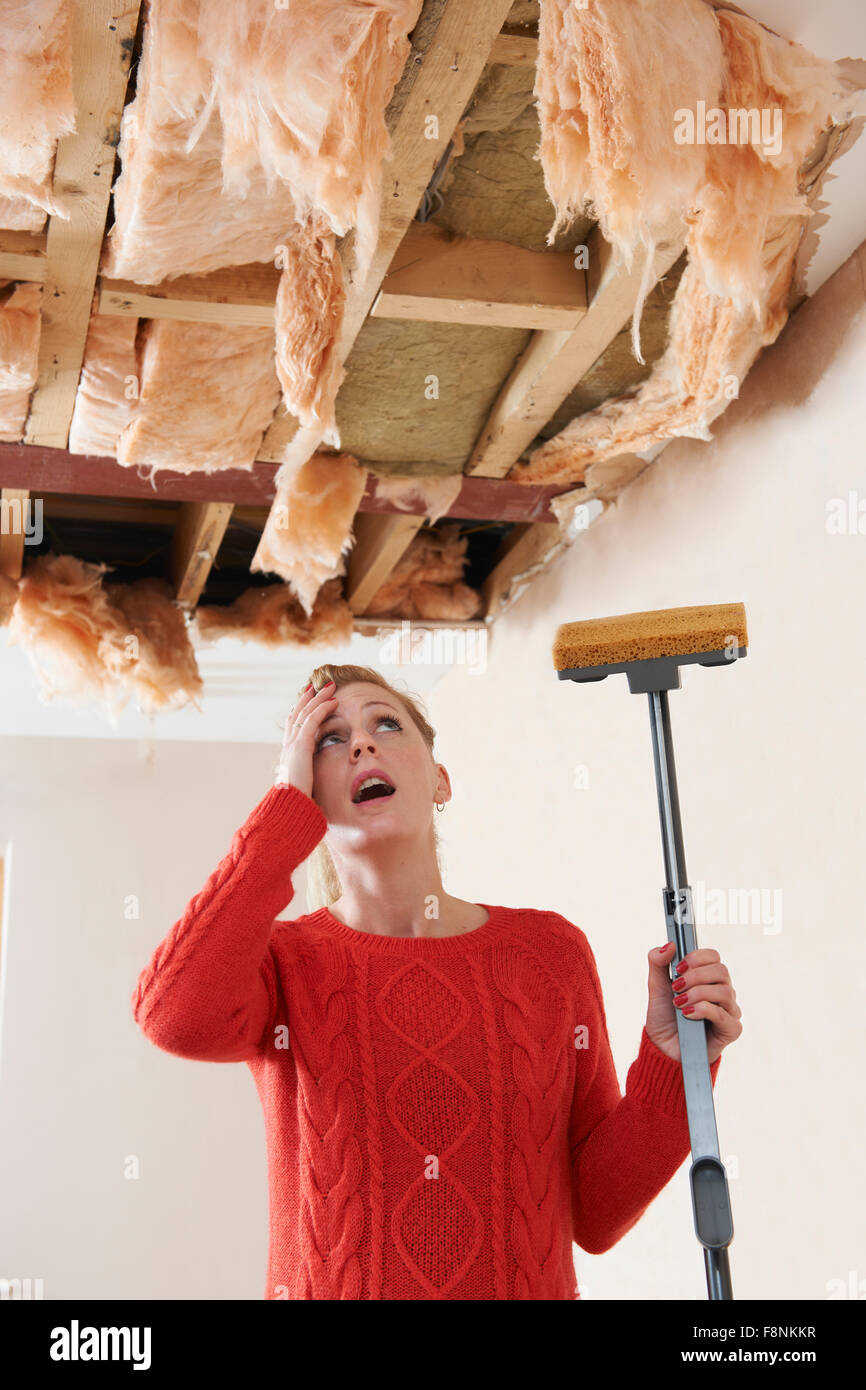Woman Holding Mop sous plafond endommagé Banque D'Images