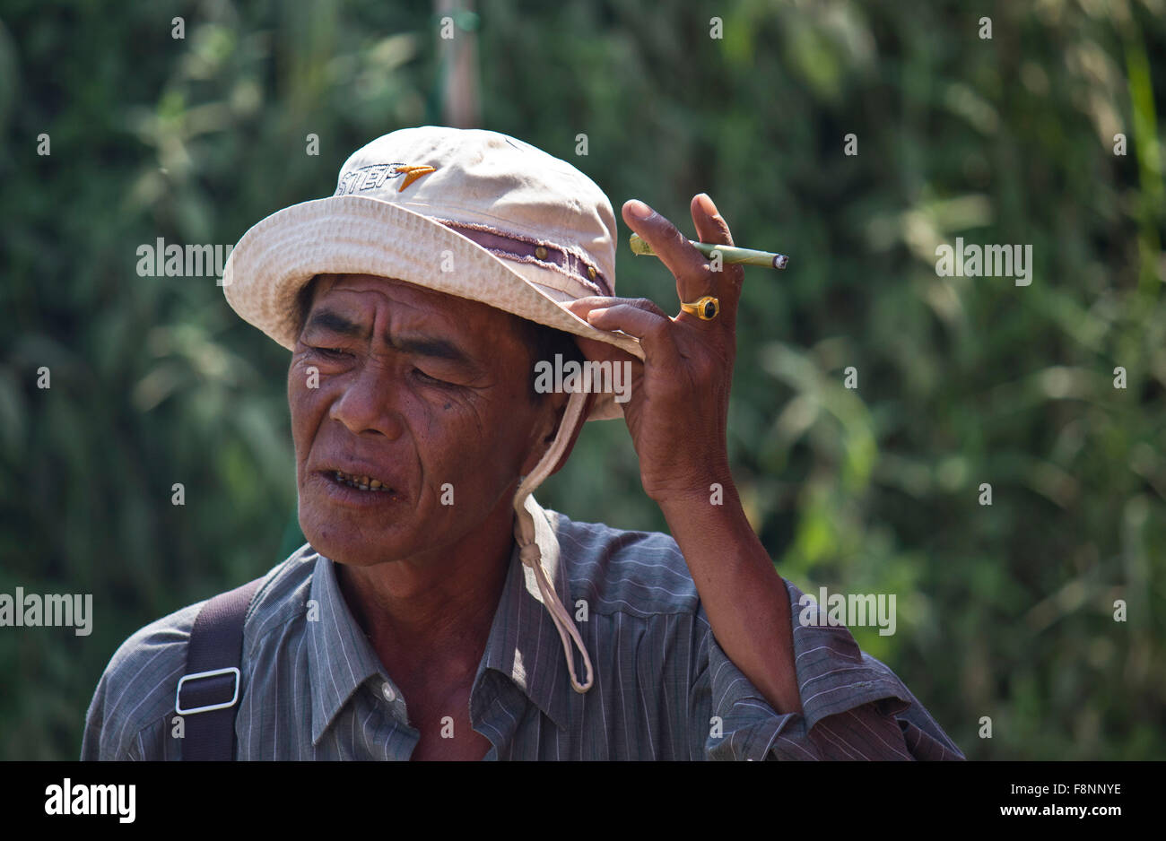 Vieux homme smiking asiatique un cigare Banque D'Images