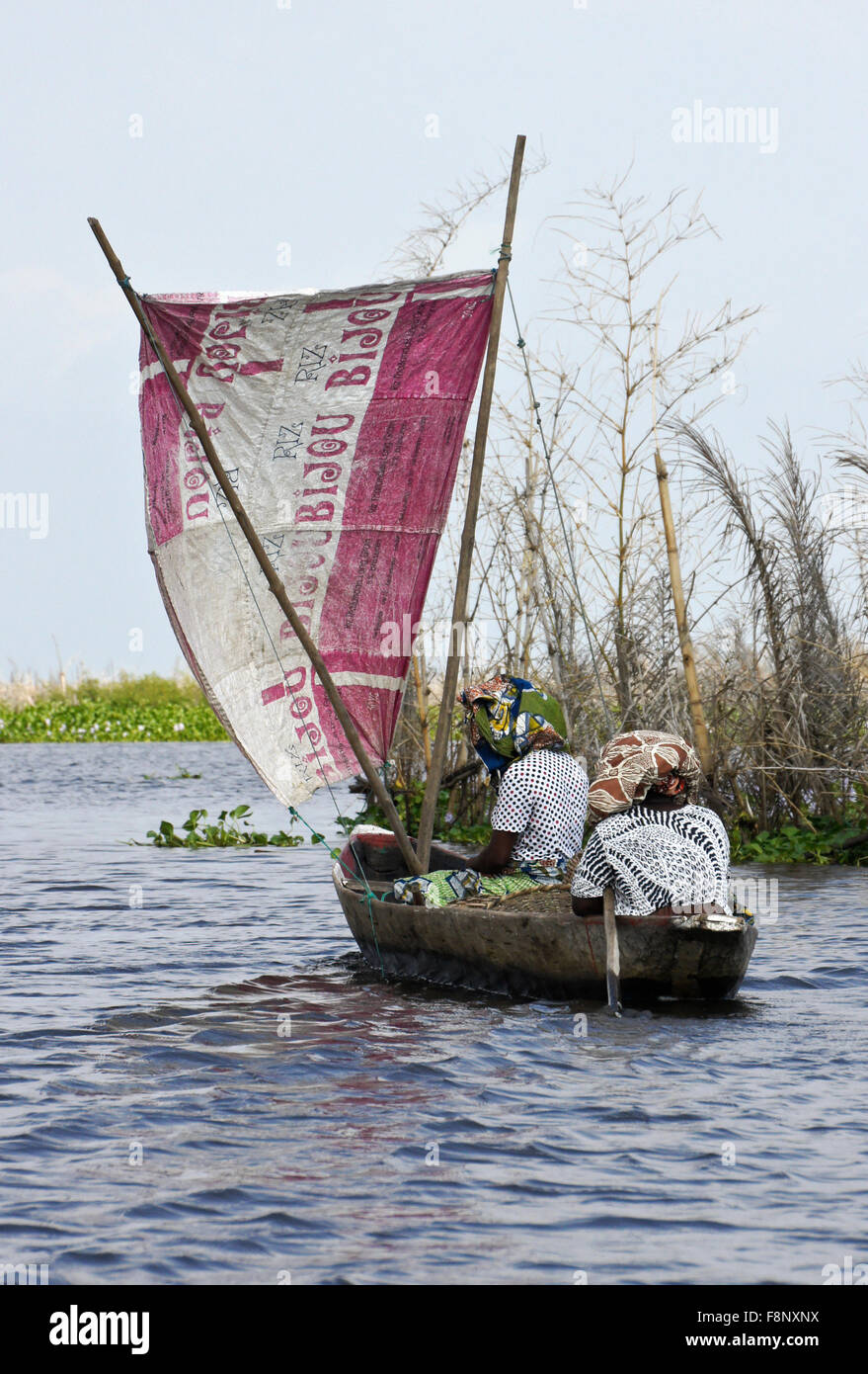 Les femmes de Ganvié village de pêcheurs en petit bateau à voile, lac Nokwe, Bénin Banque D'Images