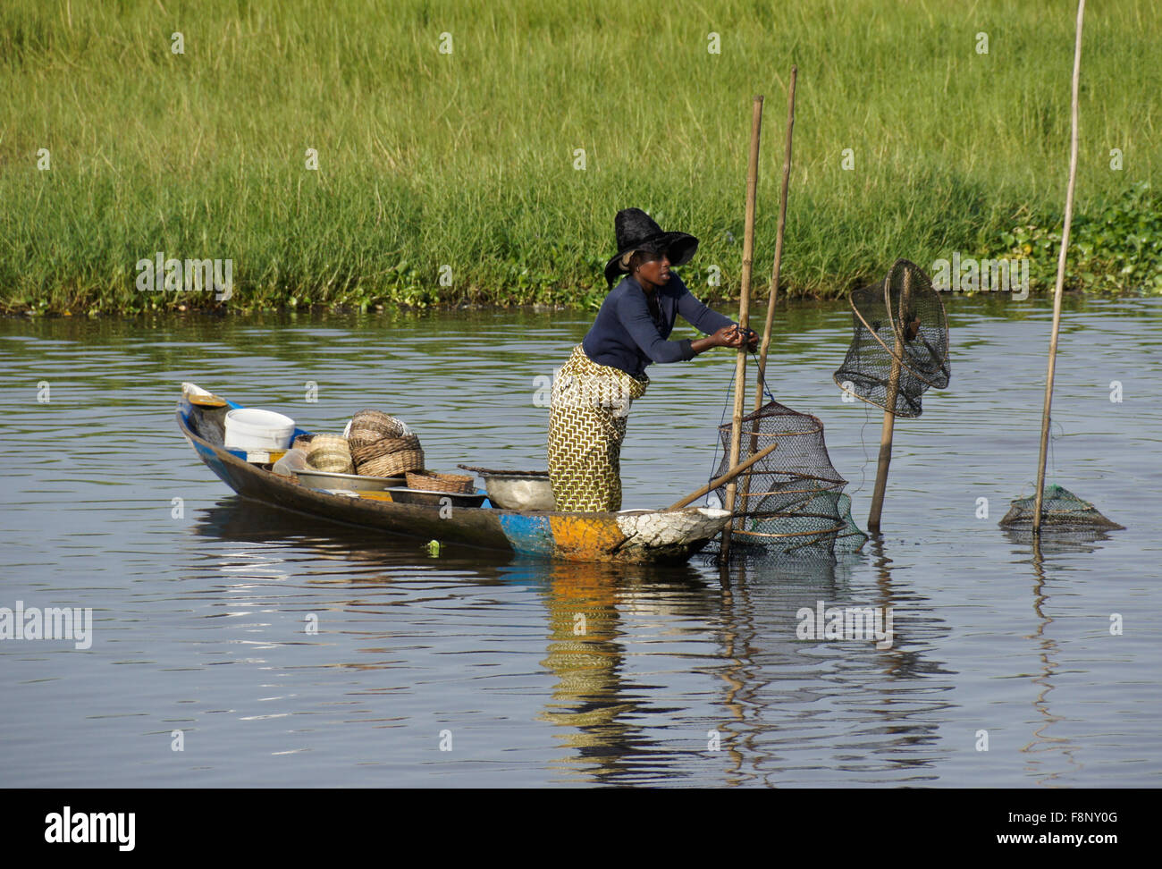 Femme de Ganvié village de pêcheurs contrôle des pièges à poissons, le lac Nokwe, Bénin Banque D'Images