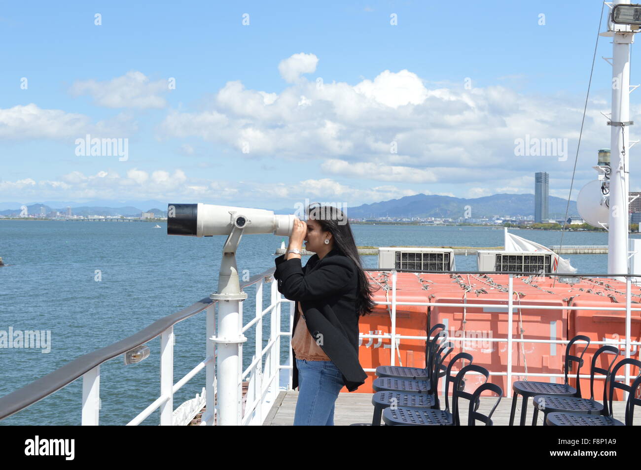 Un homme qui regarde dans un télescope en bateau dans le lac Biwako au Japon, la photo montre un beau panorama du lac, l'eau et ciel bleu Banque D'Images