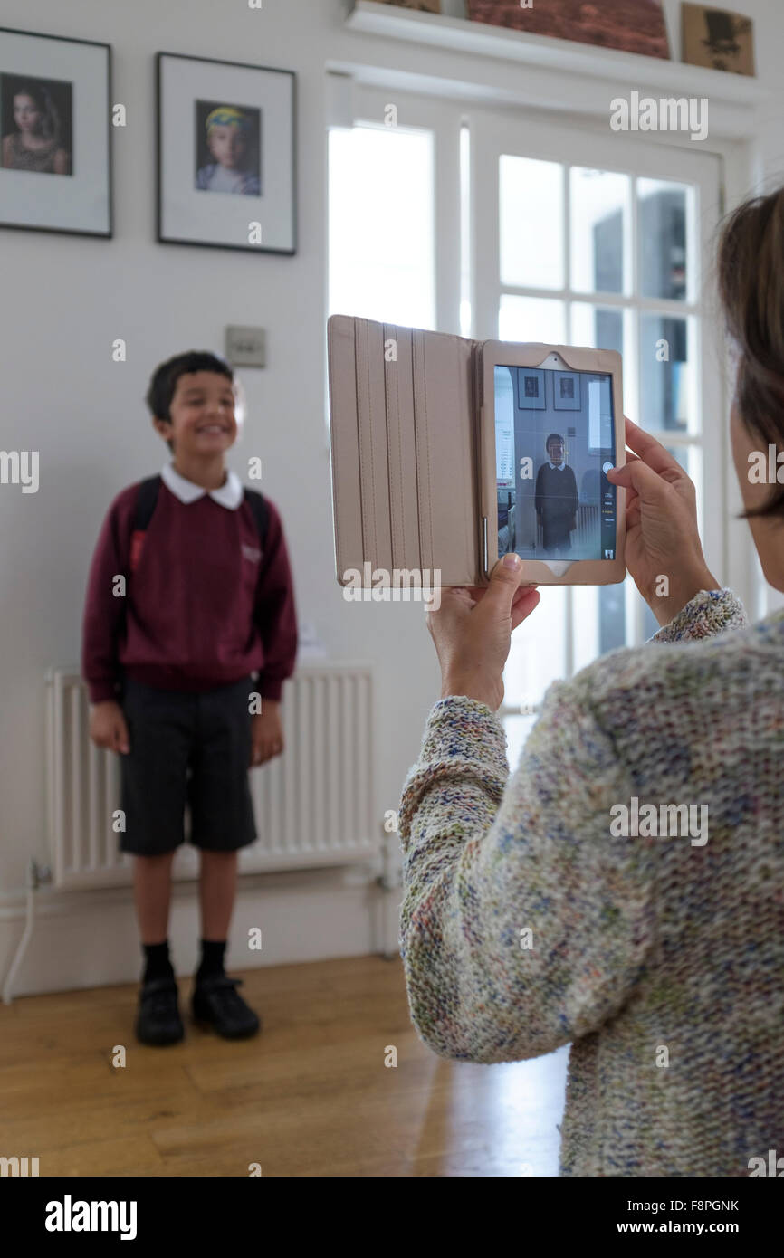 Retour de l'enfant à l'école, mère de prendre une photographie de son fils Banque D'Images