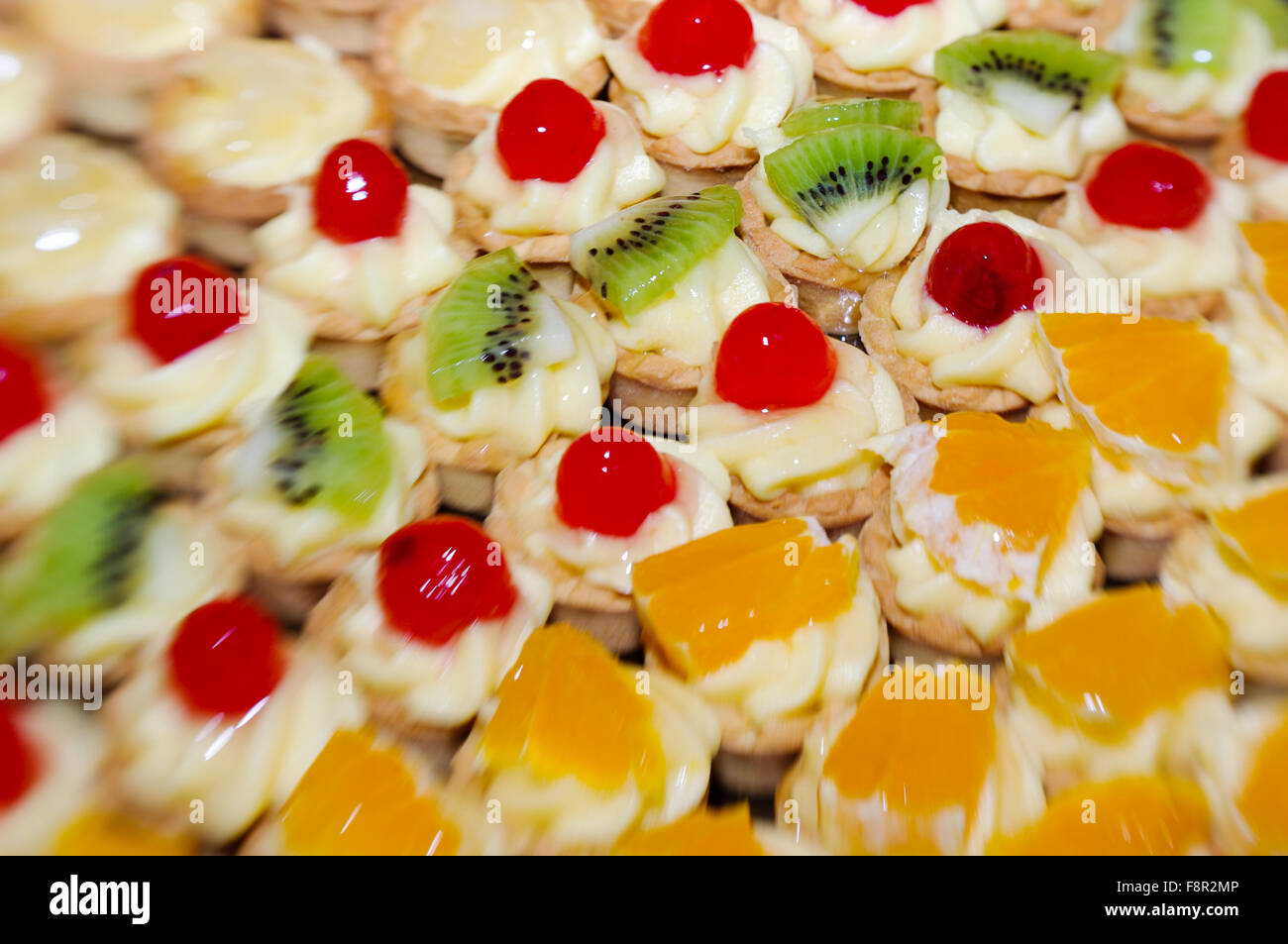 Close-up de petites tartelettes aux fruits disposés en rangées selon le fruit, l'ananas, kiwi, cerise et orange Banque D'Images