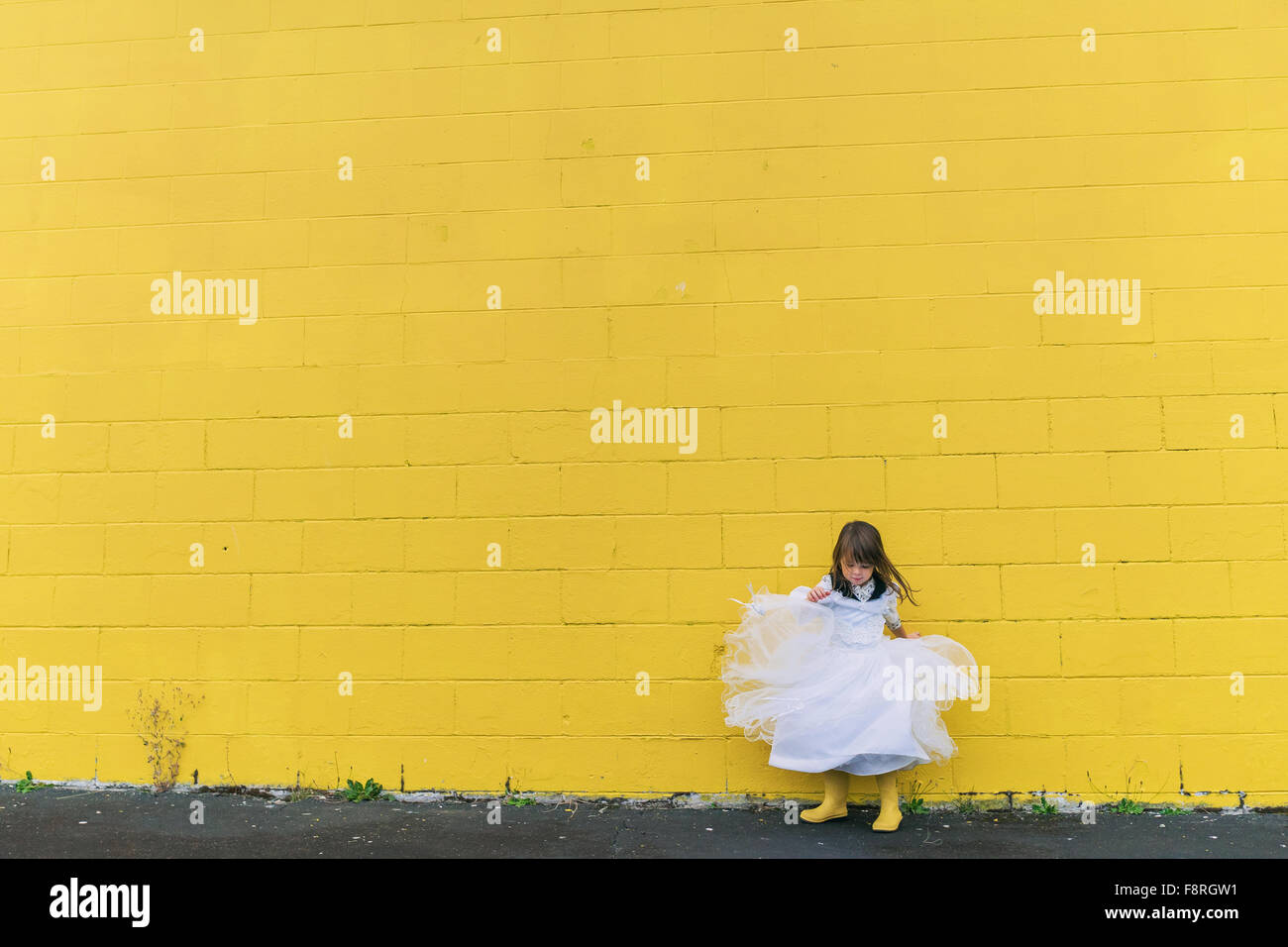 Robe fille en faisant tournoyer par mur jaune Banque D'Images