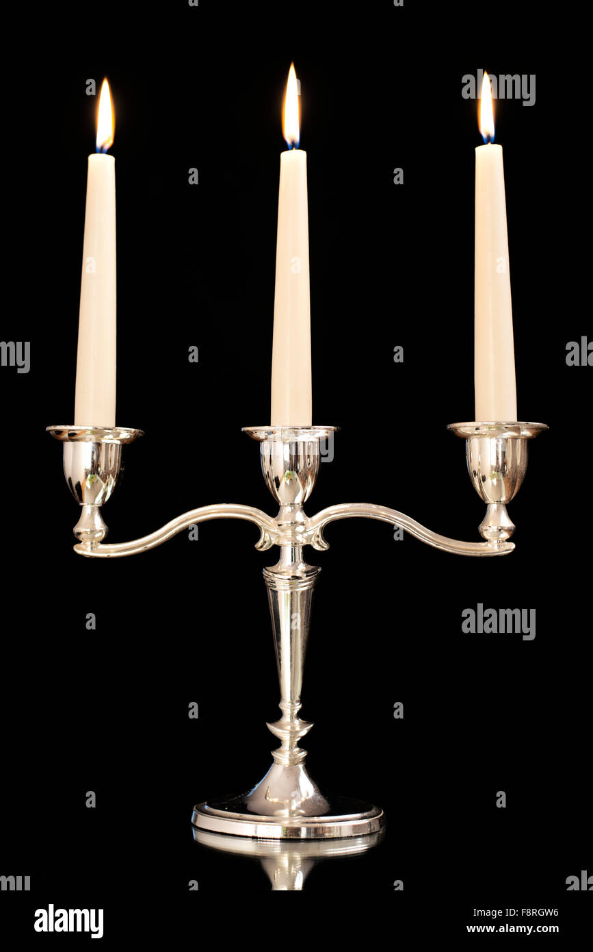 Chandelier en argent avec gravure trois bougies blanches en face de fond noir Banque D'Images