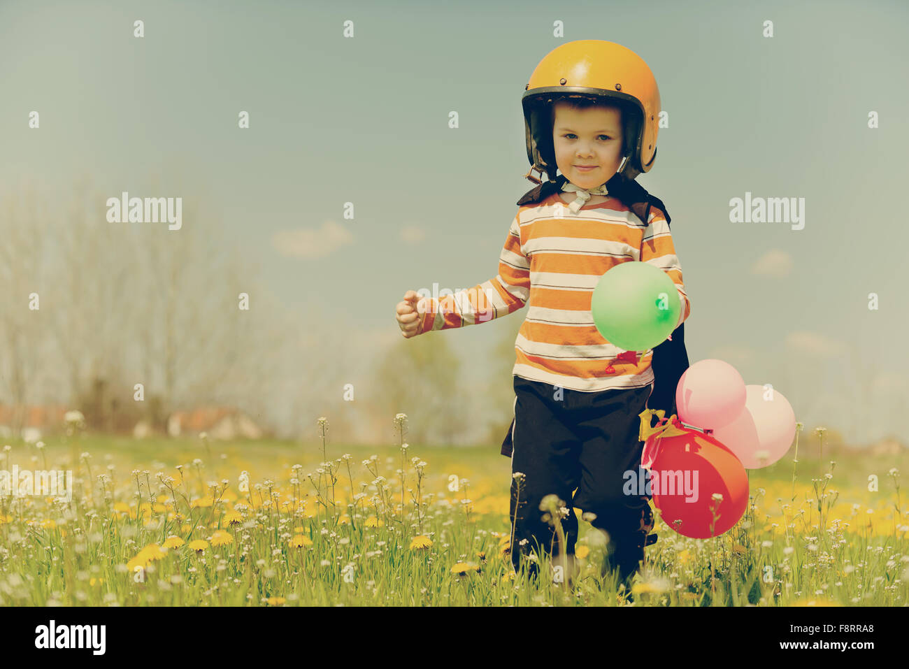 Héros orange fonctionnant avec des ballons dans la prairie et vivre la liberté. photographies look rétro. Banque D'Images