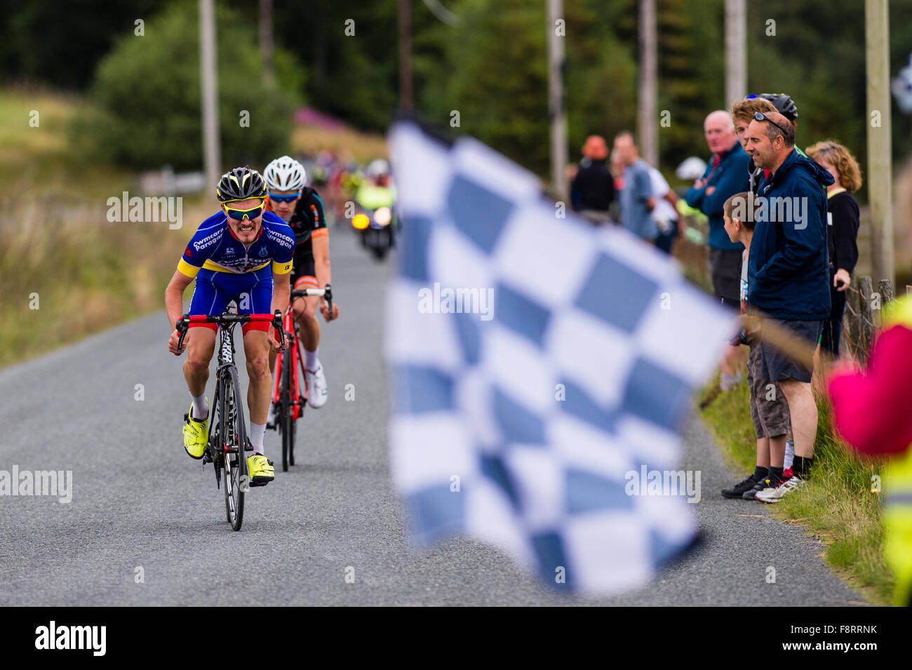 Course concurrents pour le drapeau à damier à la ligne d'arrivée à l'assemblée annuelle de la 'Tour des vallées minières Course sur route, près d'Aberystwyth, Pays de Galles, Royaume-Uni 16 Août 2015 Banque D'Images