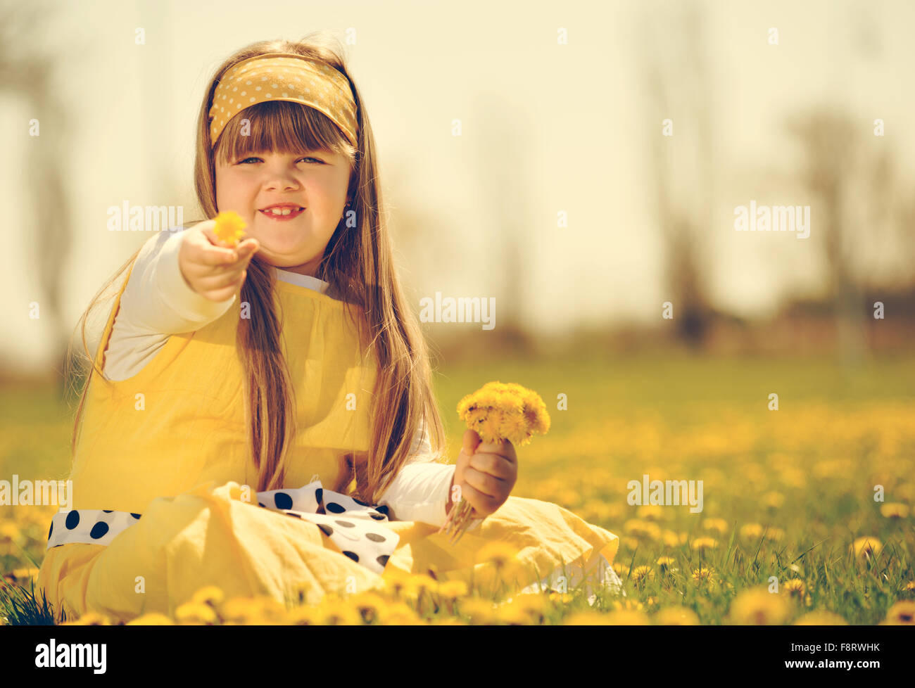 Petite fille profiter de la journée de printemps ensoleillée dans les champs de fleurs. vintage-look Banque D'Images