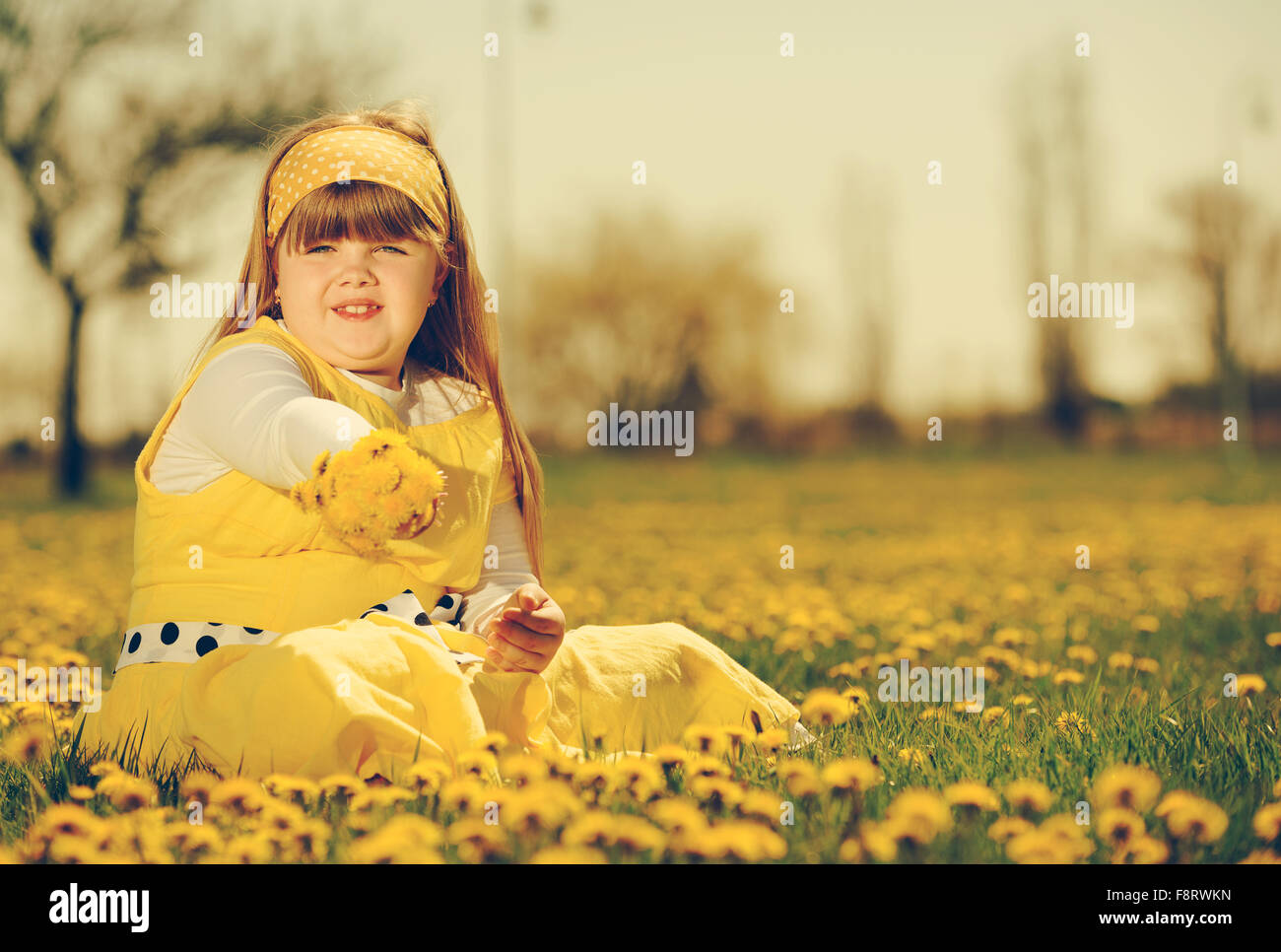 Petite fille profiter de la journée de printemps ensoleillée dans les champs de fleurs. vintage-look Banque D'Images